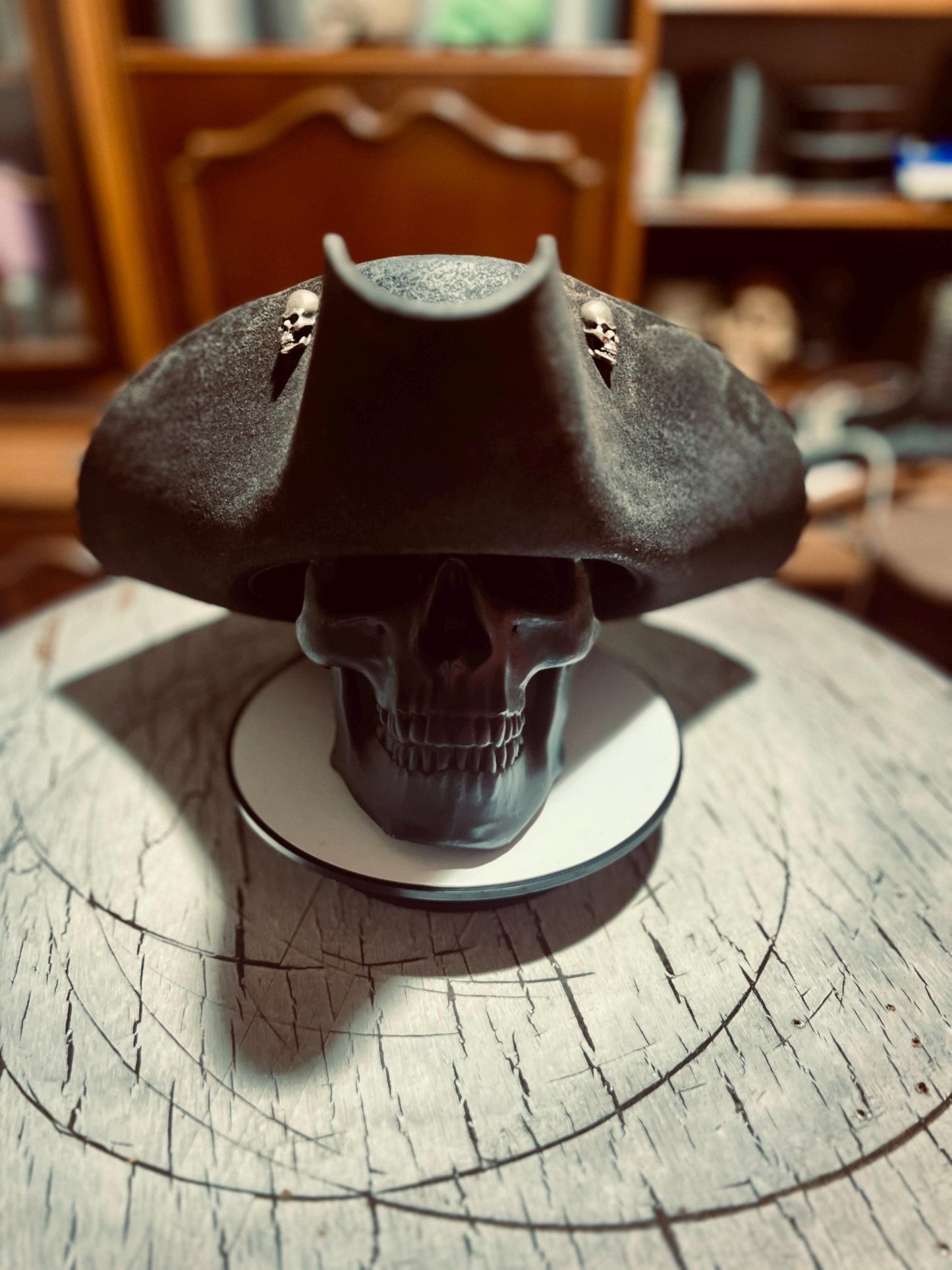 Black artisan pirate hat for adults displayed on a skull model with wooden background