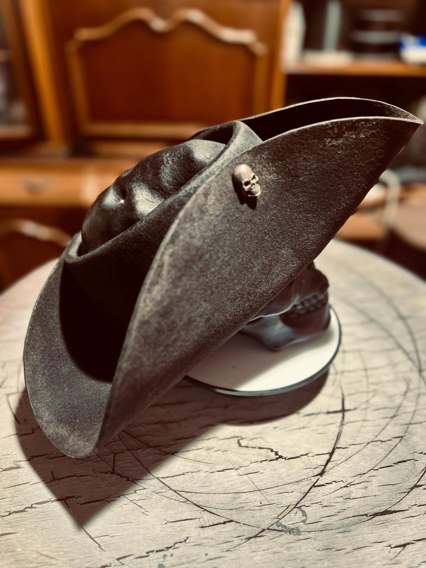 Black artisan pirate hat for adults with skull embellishment displayed on wooden surface