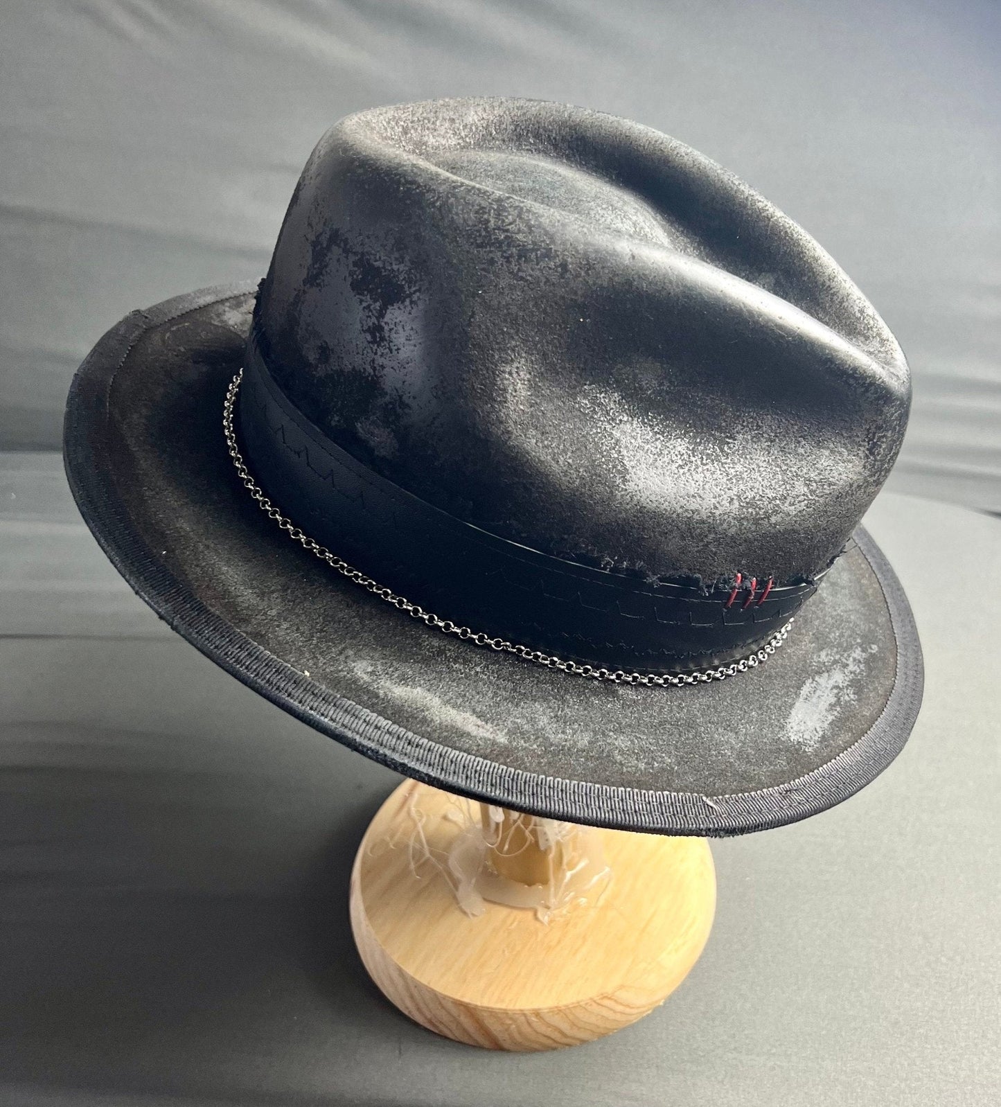 Artisan vintage men's hat in black with chain detail and textured finish on a wooden stand