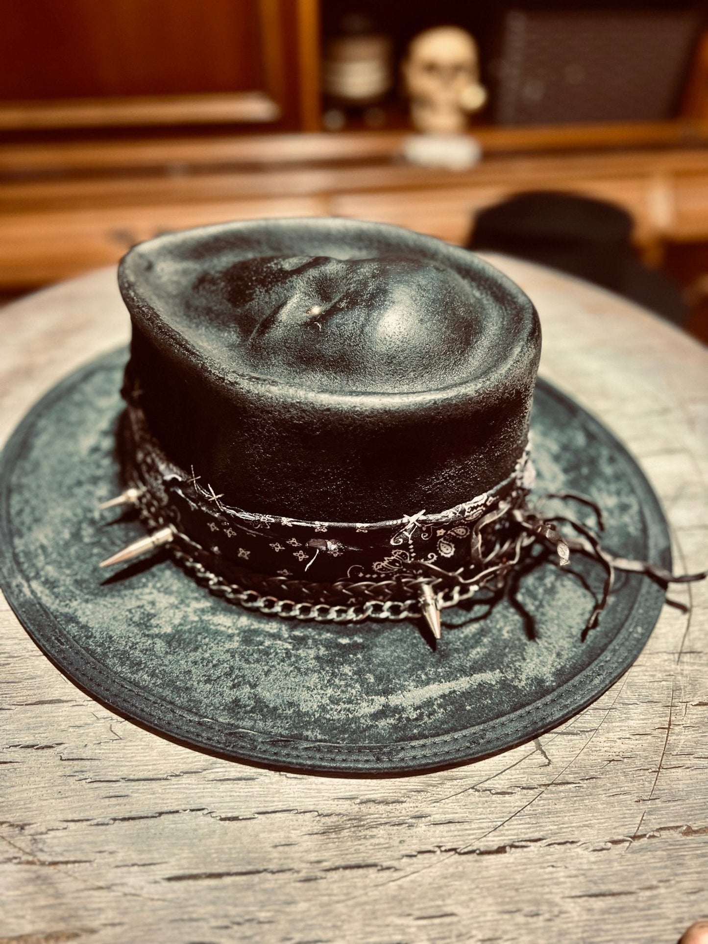 JonHats authentic distressed skull hat in black with chains and spikes on wooden surface