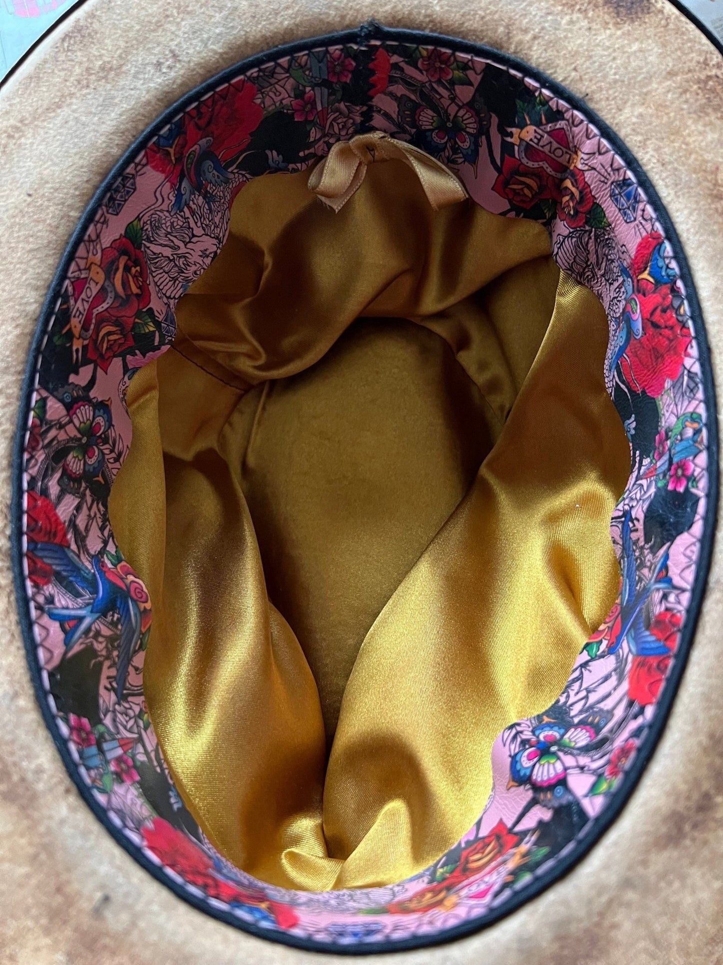 Inside view of JonHats boho vintage distressed hat featuring gold satin lining and floral patterned trim