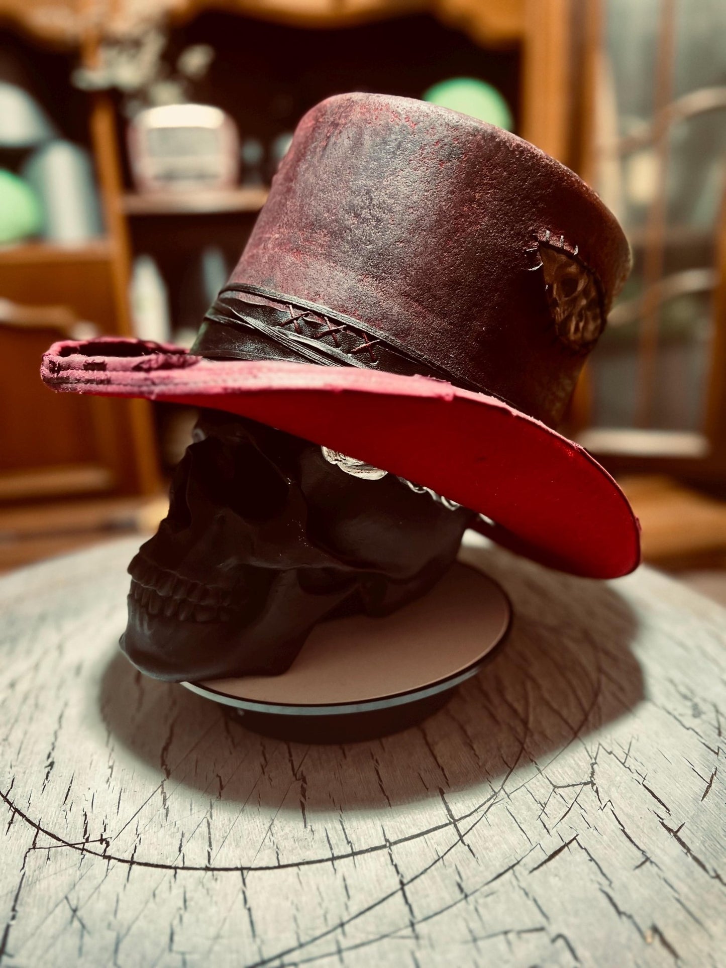 JonHats custom distressed top hat in red and black with worn leather details on skull display