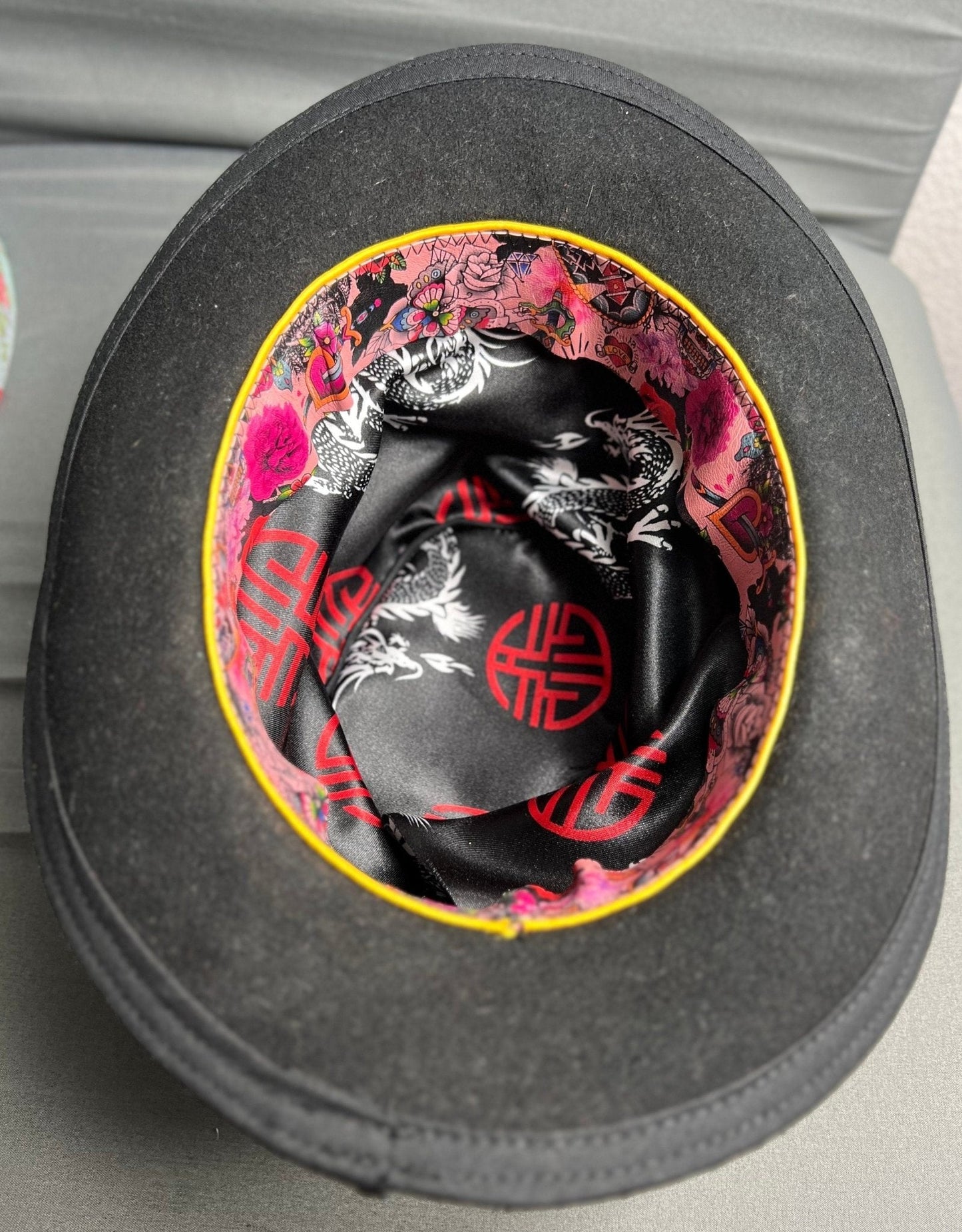 Inside view of a JonHats handmade distressed undertaker hat showing vibrant dragon and floral print lining