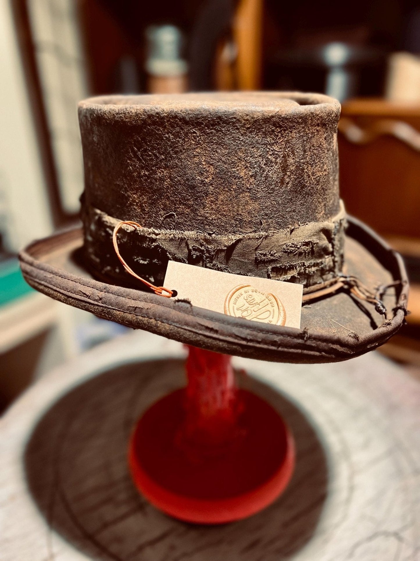 Handmade western hat by JonHats with distressed leather and rugged vintage design on display stand