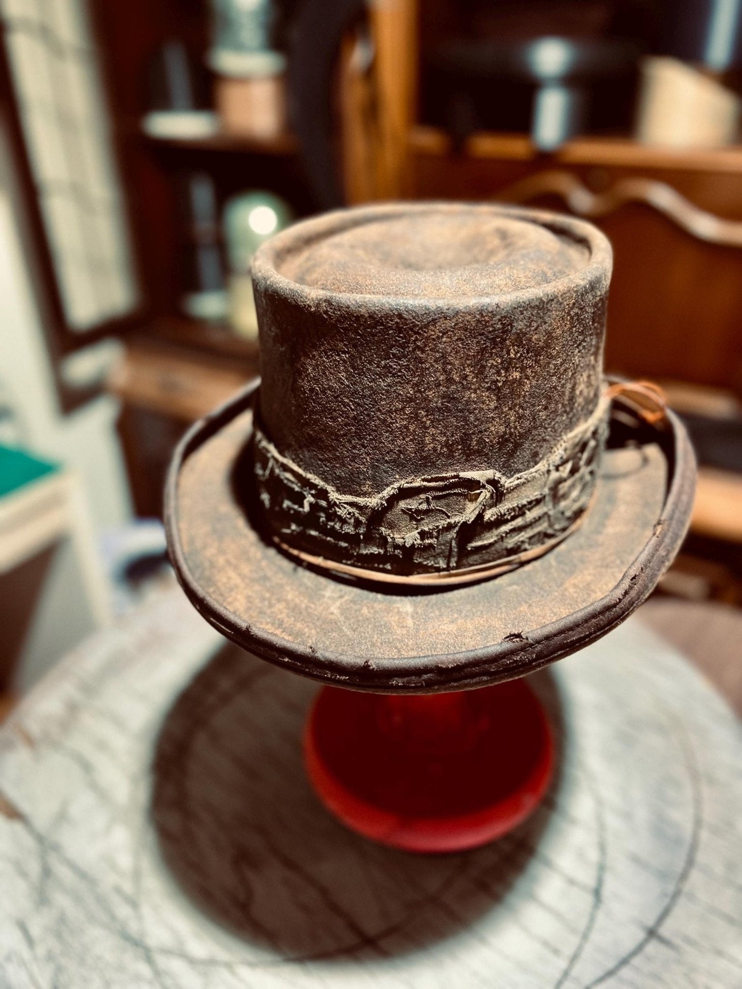 JonHats handmade western hat in distressed brown leather with decorative band on display stand