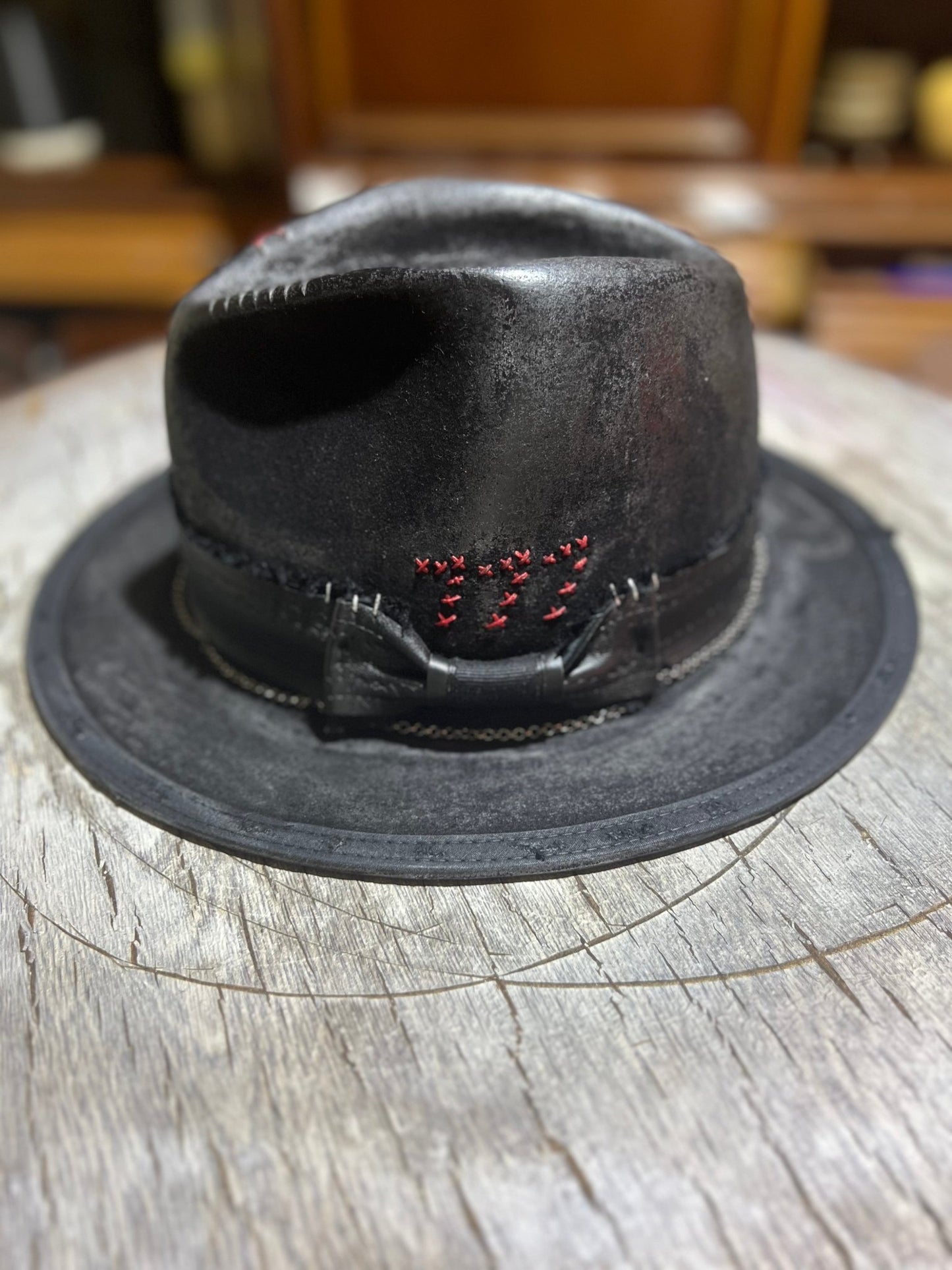 Black leather Las Vegas style vintage hat with red 777 stitching and a bowband on wooden surface