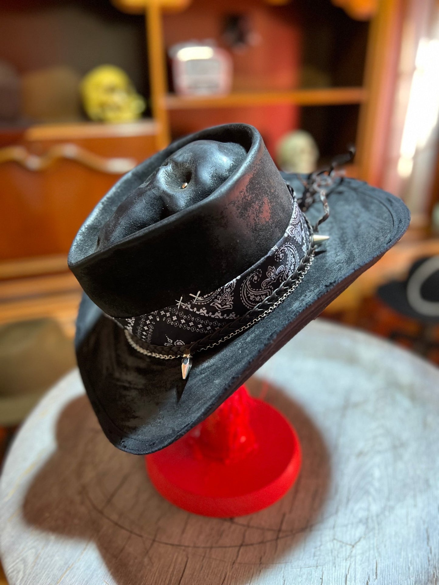 JonHats black skull themed cowboy hat with decorative band and silver skull accents on red stand