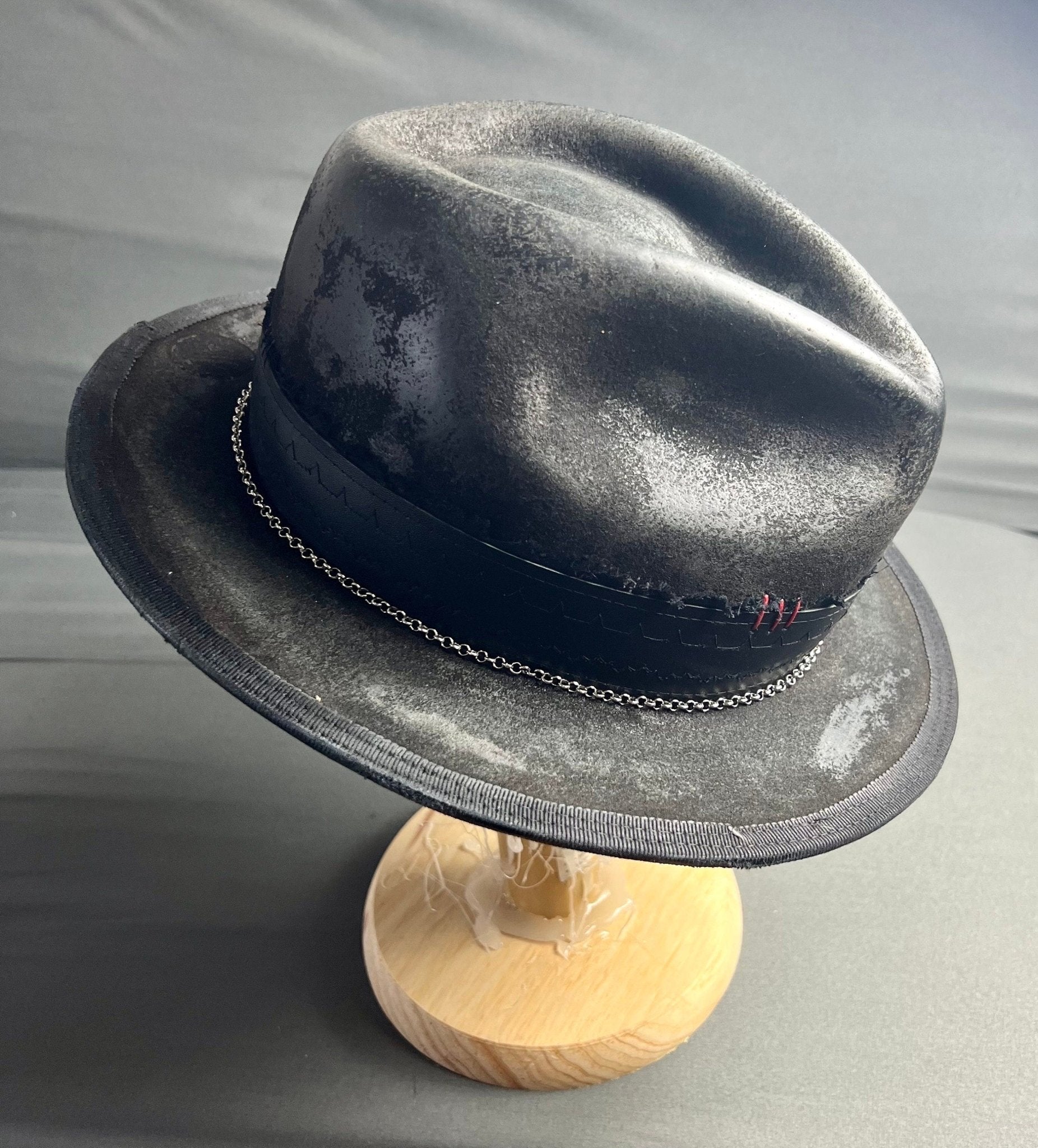Artisan vintage men's hat in black with chain detail and textured finish on a wooden stand