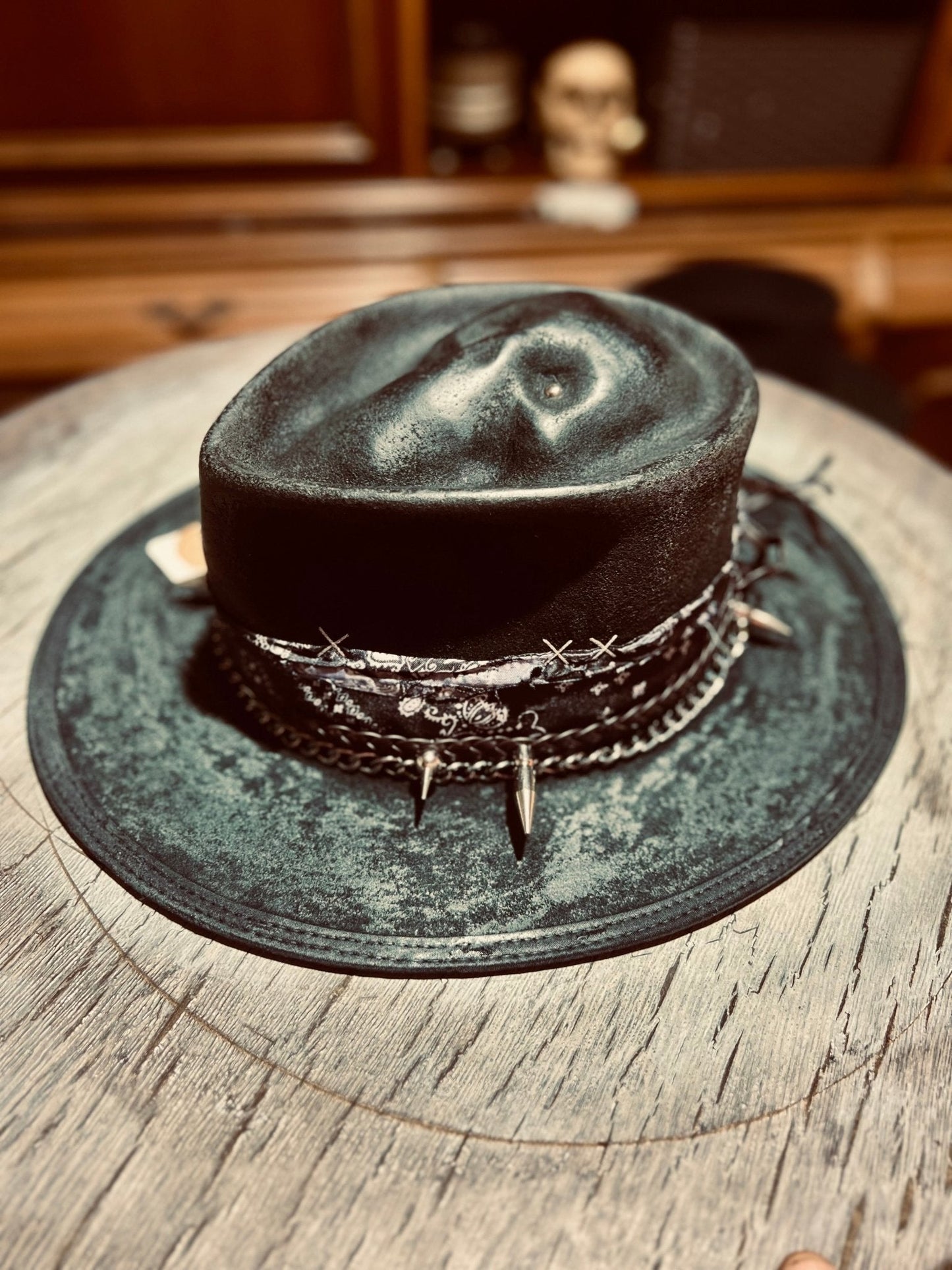 JonHats authentic distressed skull hat featuring barbed wire and spike detailing on a rustic table