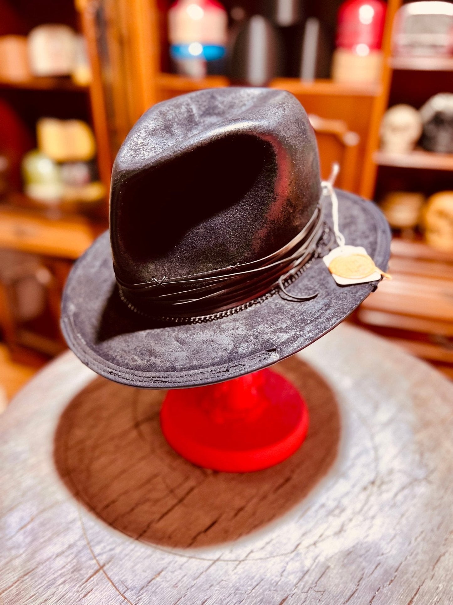 Authentic handcrafted vintage hat in dark leather style with detailed band on red display stand