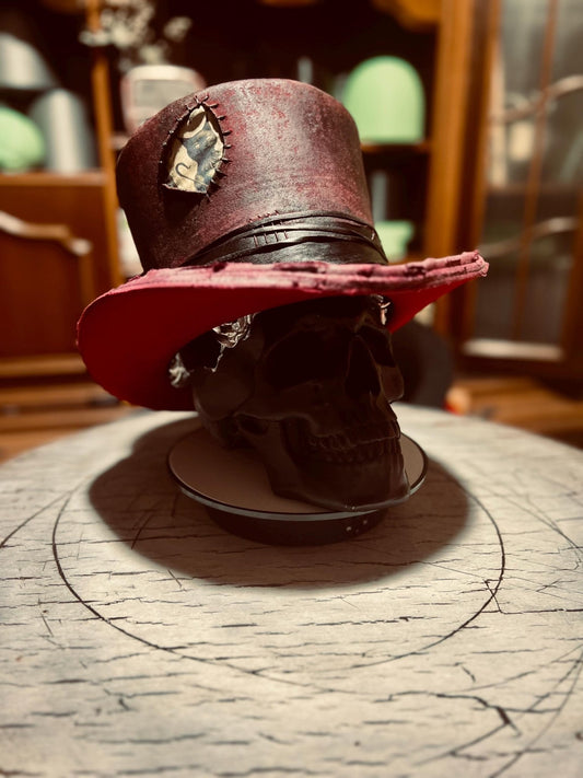 Custom distressed top hat in red with black accents displayed on a black skull model by JonHats