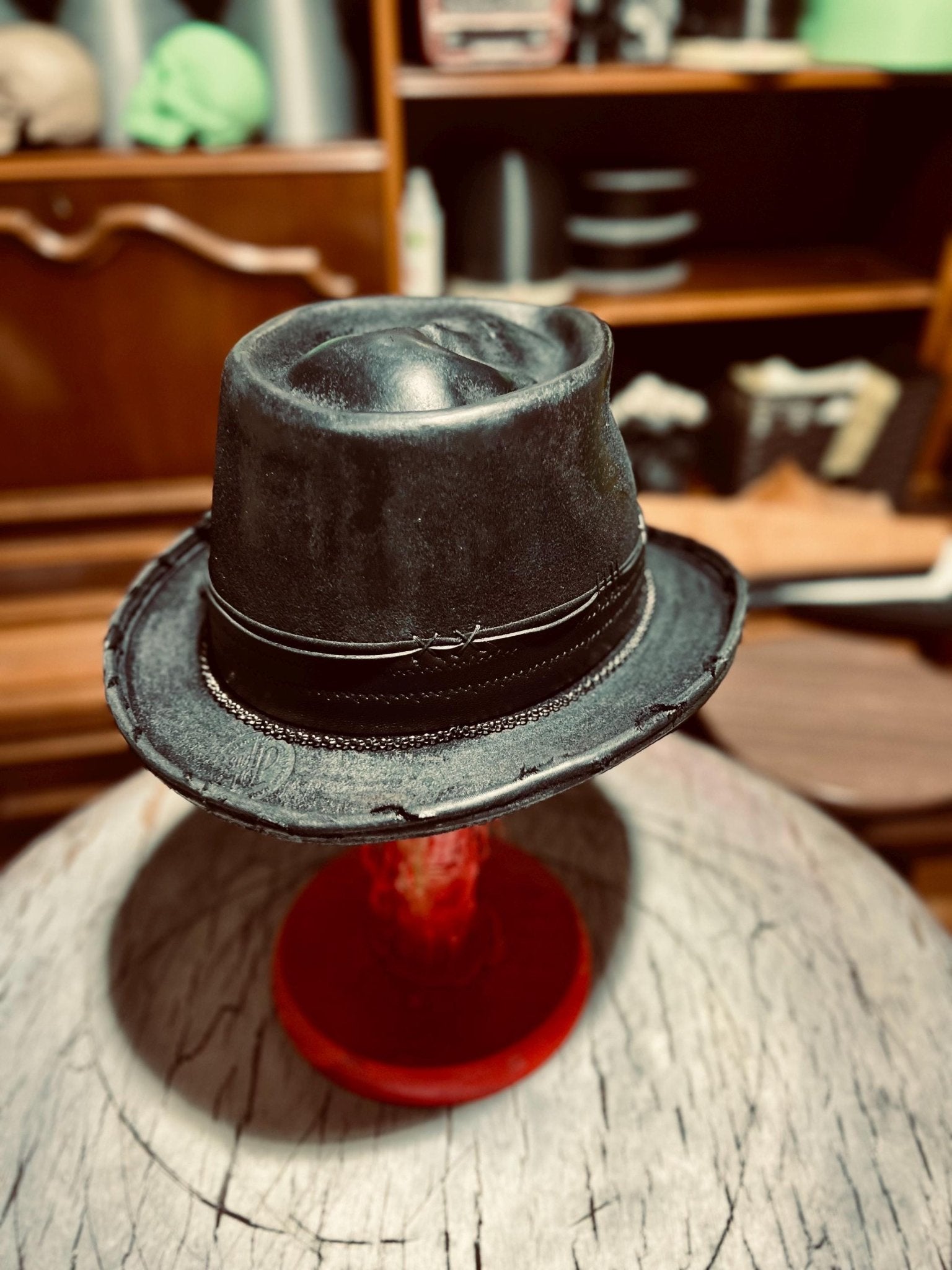 JonHats black handmade distressed fedora with leather band on display stand