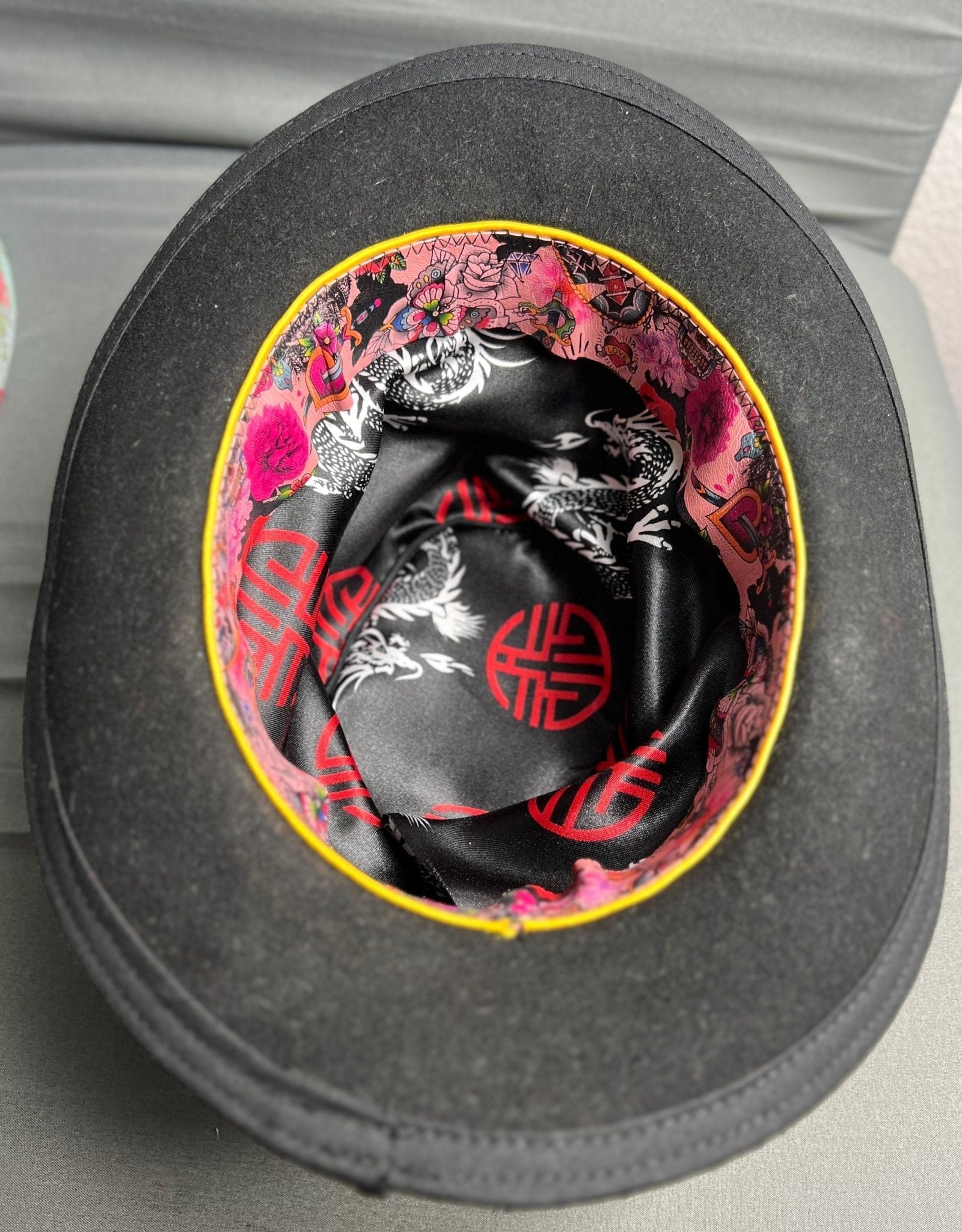 Inside view of a JonHats handmade distressed undertaker hat showing vibrant dragon and floral print lining
