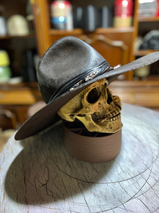 Handmade punk apocalyptic hat resting on a skull display with a wide brim and decorative band