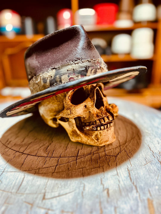Handmade vintage distressed hat displayed on a decorative skull on wooden surface by JonHats