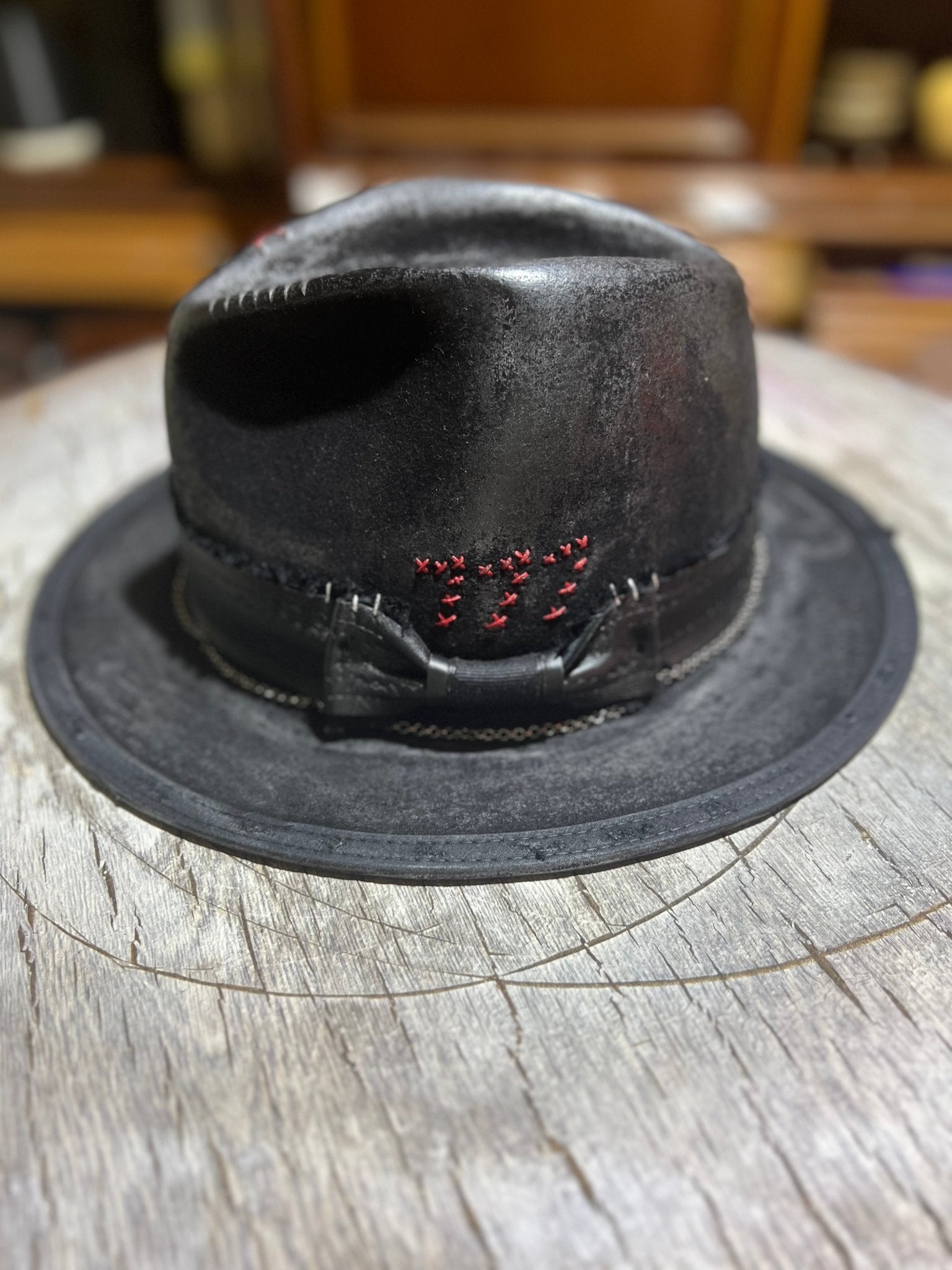 Black leather Las Vegas style vintage hat with red 777 stitching and a bowband on wooden surface