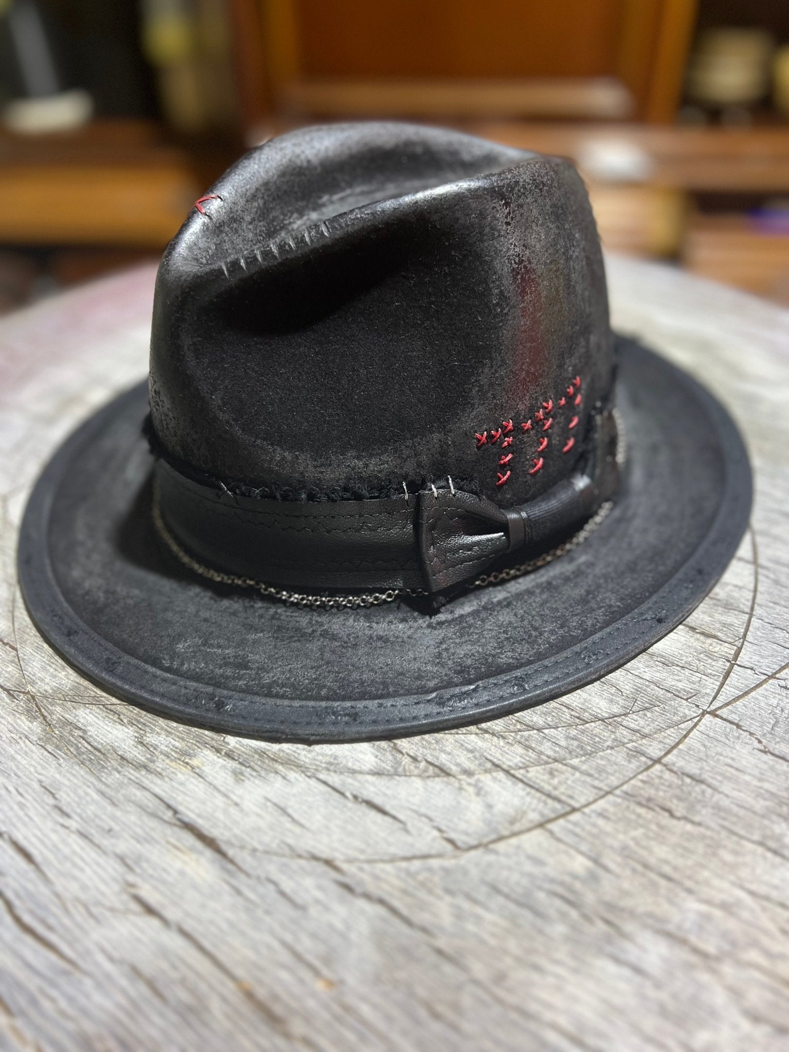 JonHats black Las Vegas style vintage hat with stitched red details and leather band on wooden surface