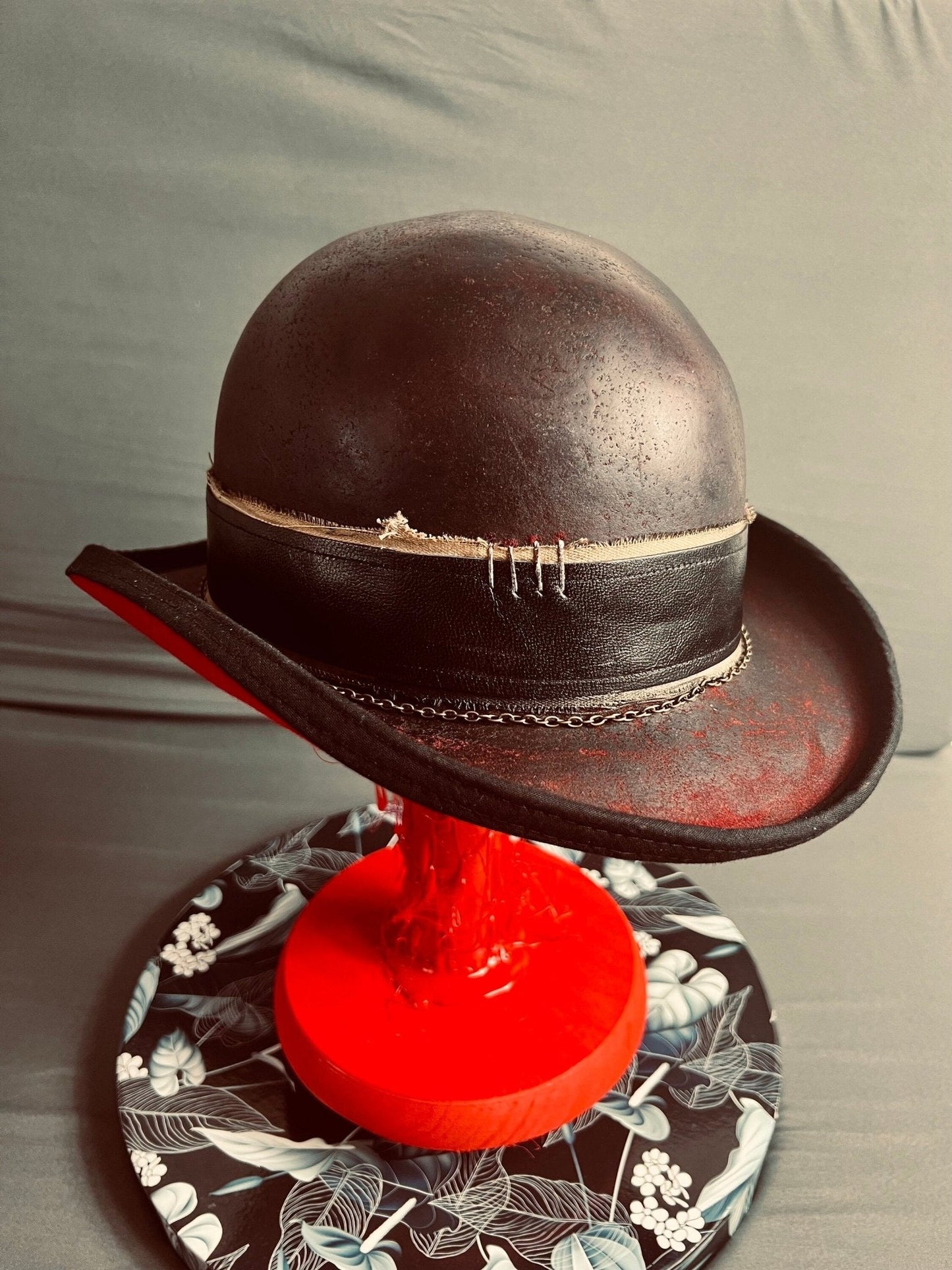 Luxury bespoke vintage fedora hat with distressed black leather and stitched band on red stand