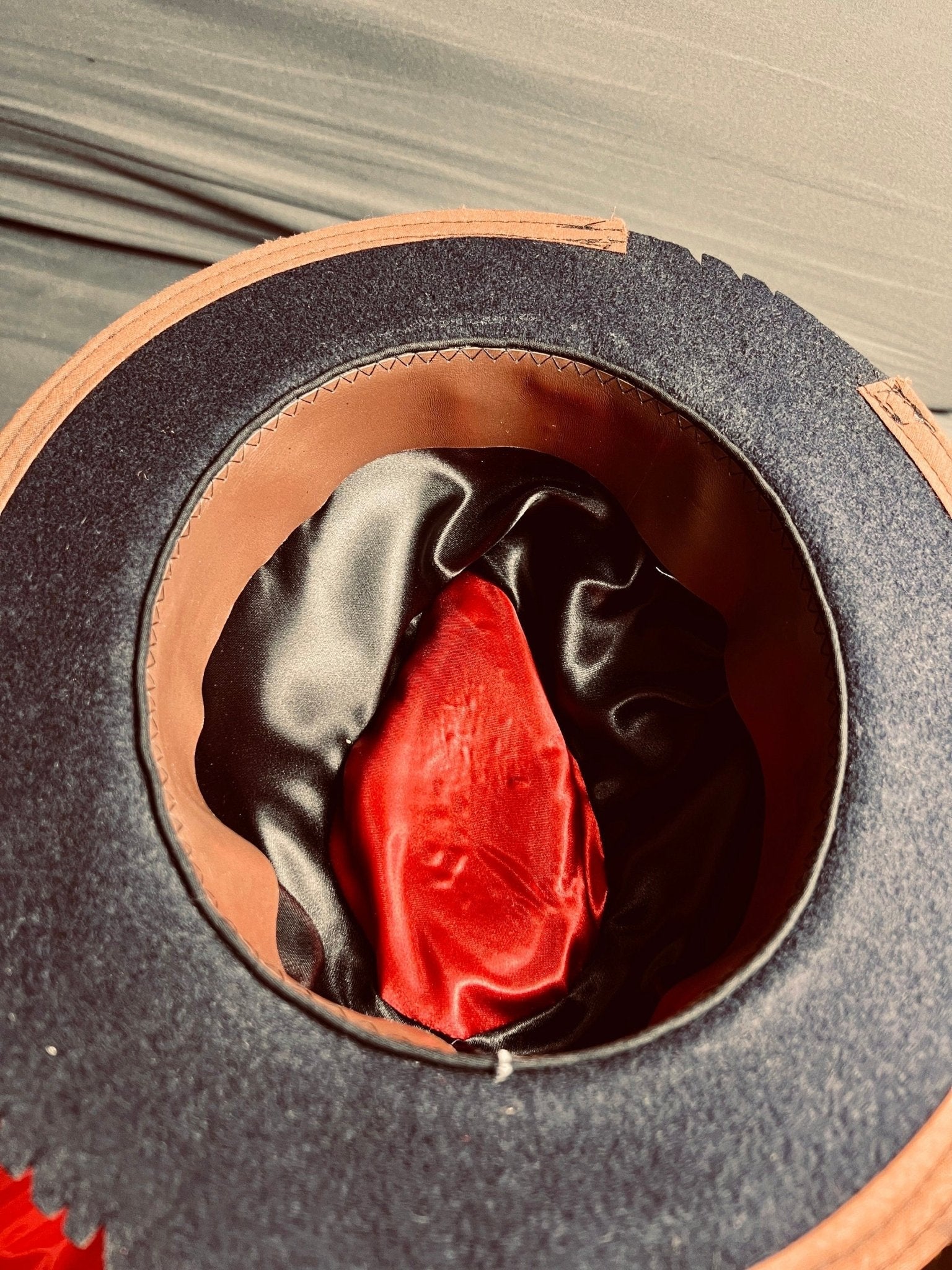 Inside view of vintage artisan skater hat showing black and red satin lining with brown trim